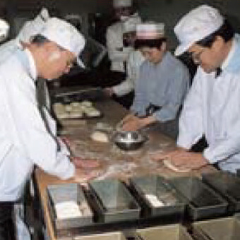 タカキベーカリー研修センターでパン作りを体験する小倉昌男（左）（1997年）